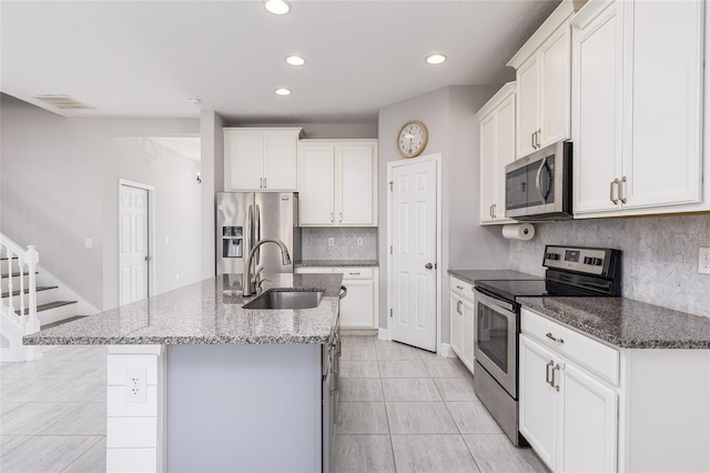 kitchen featuring tasteful backsplash, a kitchen island with sink, white cabinets, sink, and stainless steel appliances