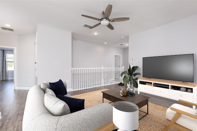 living room featuring ceiling fan, hardwood / wood-style floors, and a textured ceiling