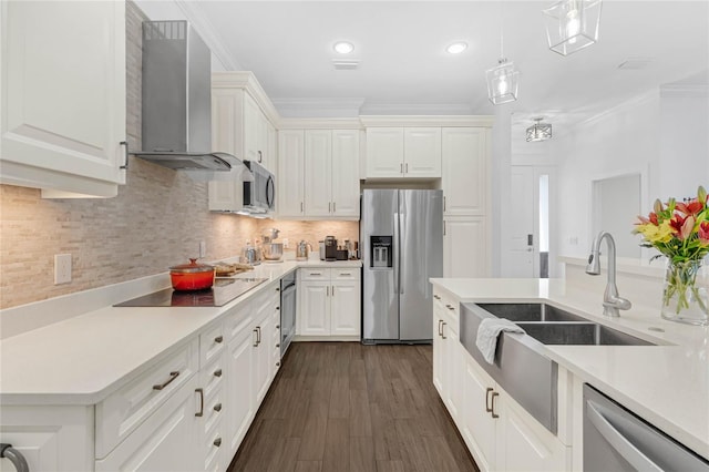 kitchen featuring wall chimney exhaust hood, stainless steel appliances, crown molding, decorative light fixtures, and white cabinets