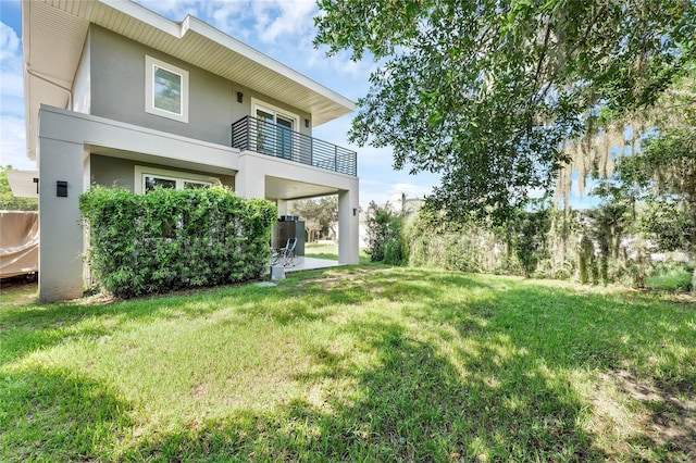 back of house with a yard, a balcony, and a patio