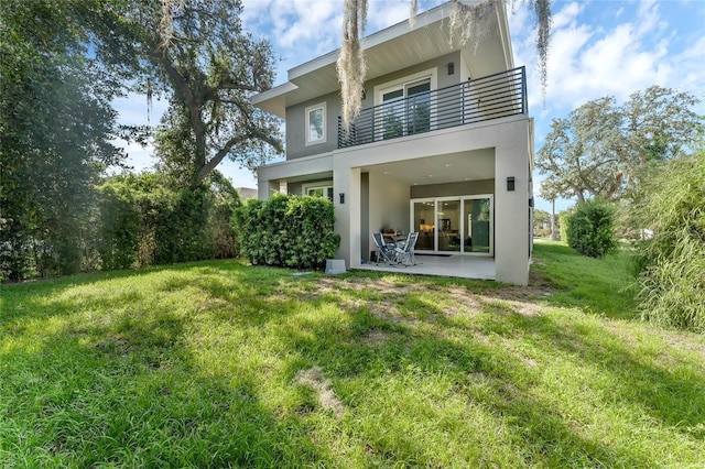 back of house with a balcony, a yard, and a patio