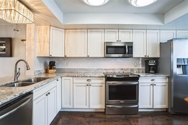 kitchen with a sink, light stone counters, appliances with stainless steel finishes, decorative backsplash, and dark wood-style flooring