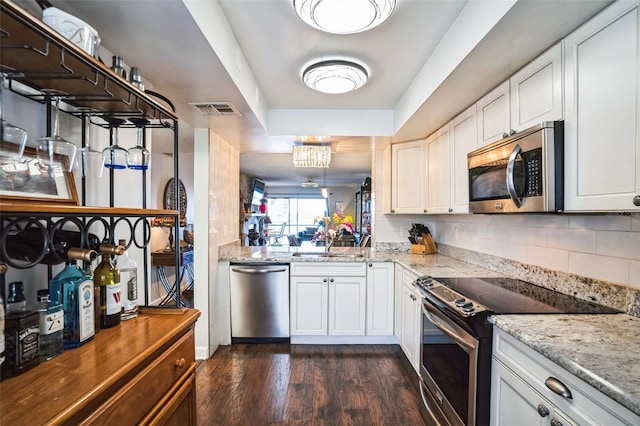 kitchen featuring white cabinetry, tasteful backsplash, light stone counters, dark hardwood / wood-style flooring, and appliances with stainless steel finishes