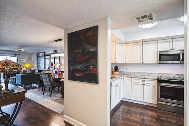 kitchen featuring light stone counters, visible vents, dark wood finished floors, appliances with stainless steel finishes, and tasteful backsplash