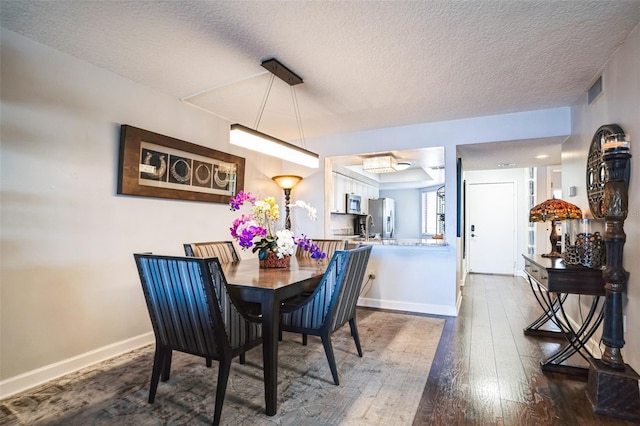 dining area featuring dark wood finished floors, visible vents, baseboards, and a textured ceiling