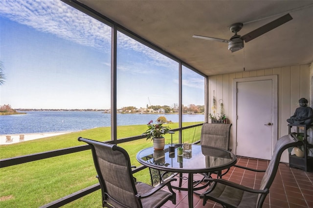 sunroom featuring ceiling fan and a water view