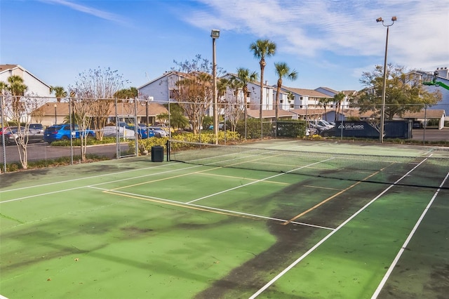 view of tennis court with fence and a residential view