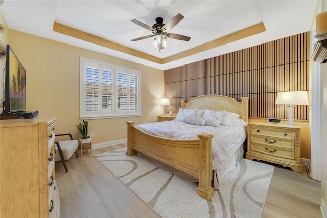 bedroom featuring a tray ceiling, ceiling fan, and light hardwood / wood-style floors