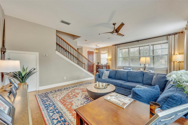 living room featuring wood-type flooring and ceiling fan with notable chandelier