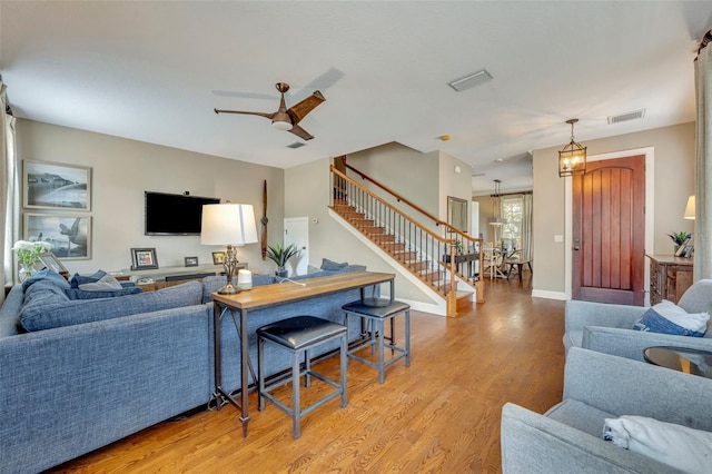 living room featuring light hardwood / wood-style floors and ceiling fan with notable chandelier