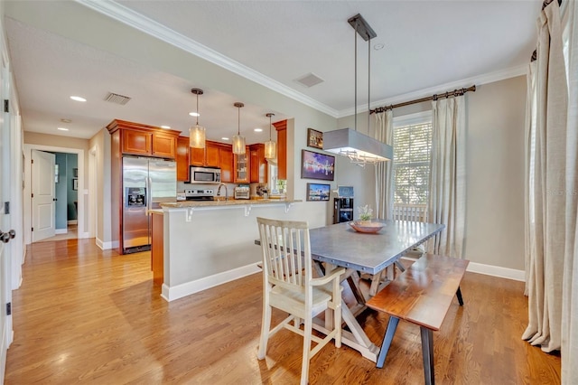 dining room with light wood-type flooring and ornamental molding