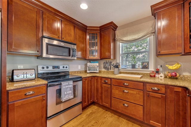 kitchen with light stone countertops, stainless steel appliances, and light wood-type flooring