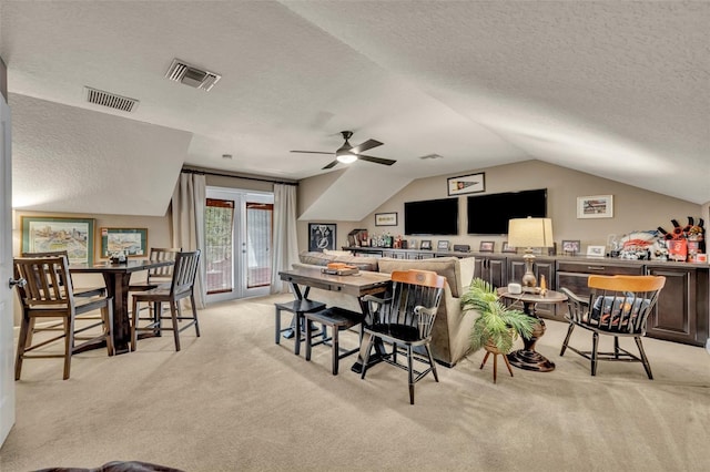 dining room featuring ceiling fan, light colored carpet, and a textured ceiling