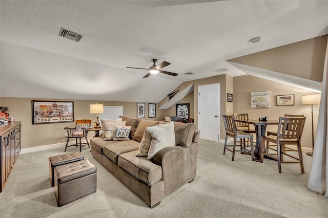 living room featuring a textured ceiling, light colored carpet, ceiling fan, and lofted ceiling