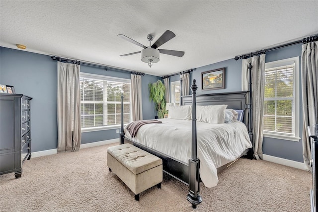 carpeted bedroom featuring multiple windows, a textured ceiling, and ceiling fan