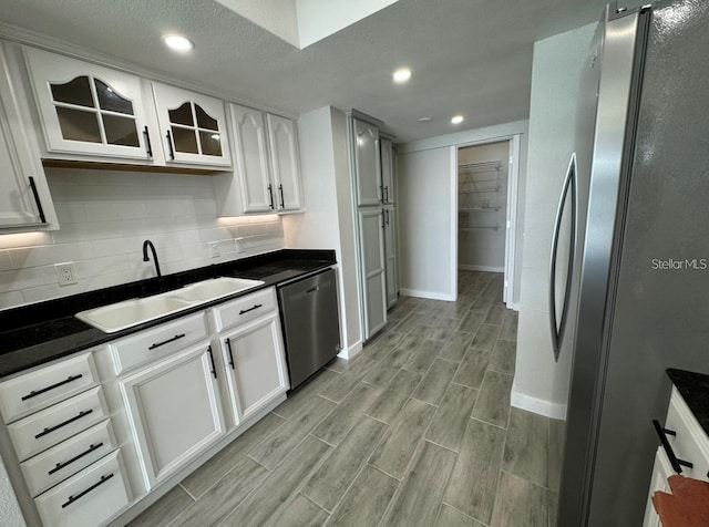 kitchen with stainless steel appliances, white cabinets, sink, and tasteful backsplash