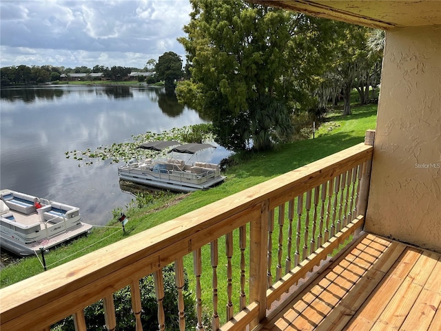 wooden terrace featuring a lawn and a water view