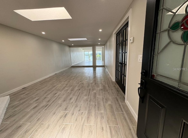 unfurnished room with light hardwood / wood-style floors and a skylight