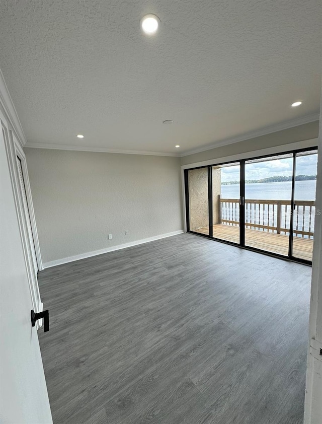 spare room featuring a textured ceiling, ornamental molding, and a water view