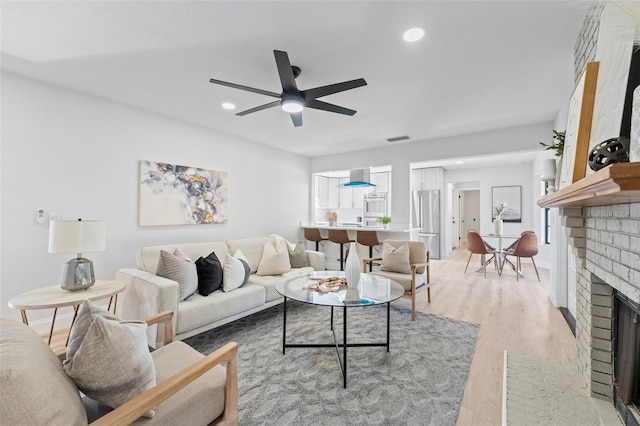 living room with a fireplace, hardwood / wood-style flooring, and ceiling fan