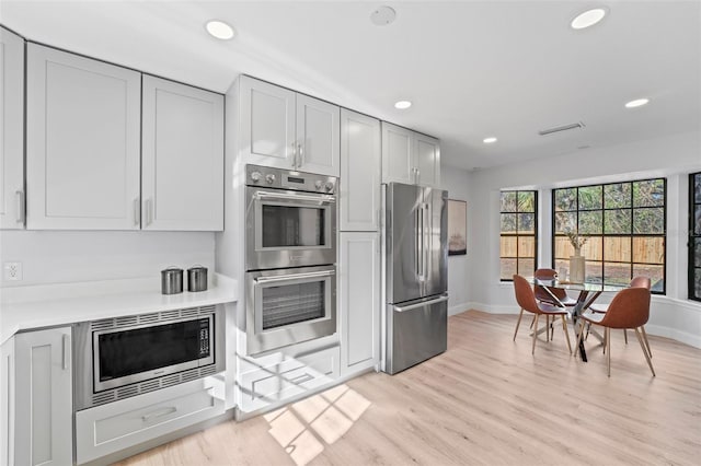 kitchen with gray cabinets, light hardwood / wood-style floors, and appliances with stainless steel finishes