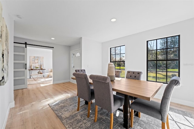 dining room with a barn door and light hardwood / wood-style flooring