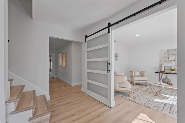 sitting room featuring a barn door and light hardwood / wood-style flooring