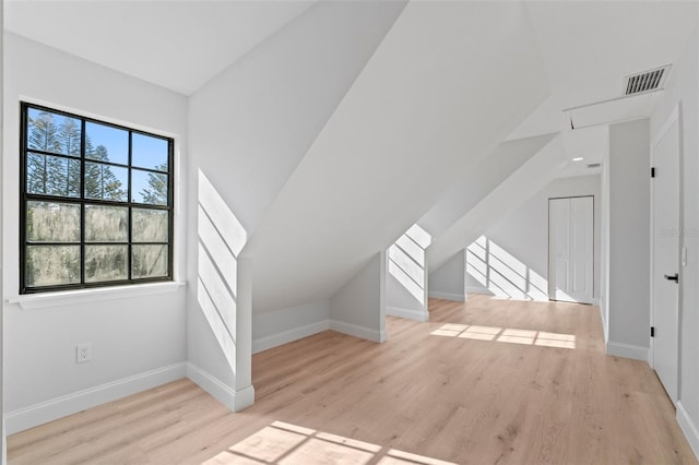 additional living space with vaulted ceiling and light wood-type flooring