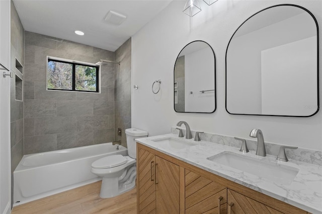 full bathroom featuring tiled shower / bath combo, toilet, wood-type flooring, and vanity