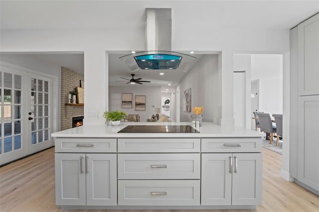 417 Main Trl, Ormond Beach, FL 32174 - kitchen with black electric stovetop, island range hood, light wood-style flooring, and light countertops