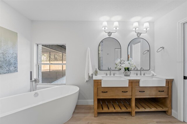 417 Main Trl, Ormond Beach, FL 32174 - bathroom featuring double vanity, wood finished floors, a freestanding bath, and baseboards