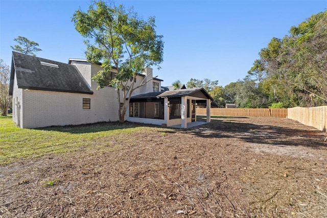 417 Main Trl, Ormond Beach, FL 32174 - rear view of property with a sunroom, brick siding, roof with shingles, and a chimney
