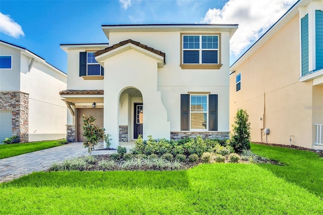 view of front of house featuring a garage, stone siding, decorative driveway, stucco siding, and a front lawn