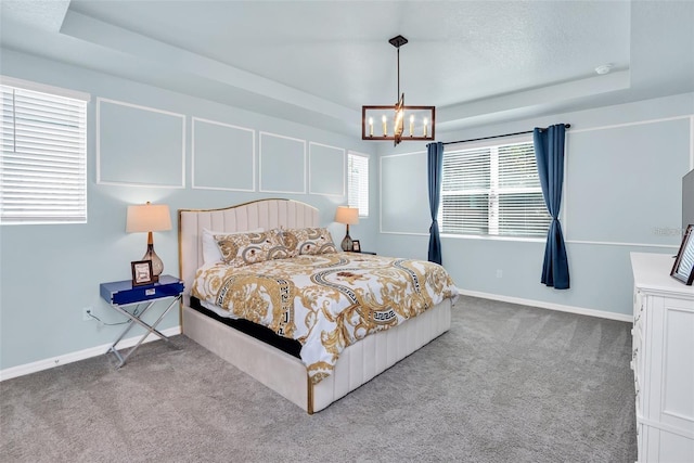 bedroom featuring light colored carpet, a raised ceiling, and a notable chandelier