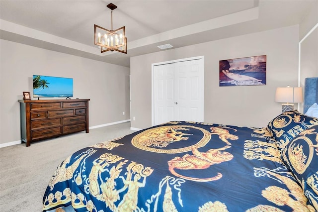 bedroom featuring a tray ceiling, a closet, carpet floors, and a chandelier