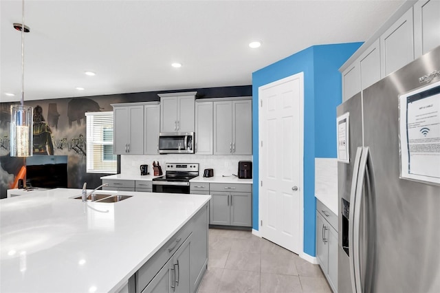 kitchen featuring decorative backsplash, stainless steel appliances, sink, gray cabinets, and hanging light fixtures