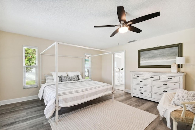 bedroom with a textured ceiling, connected bathroom, ceiling fan, and dark hardwood / wood-style floors