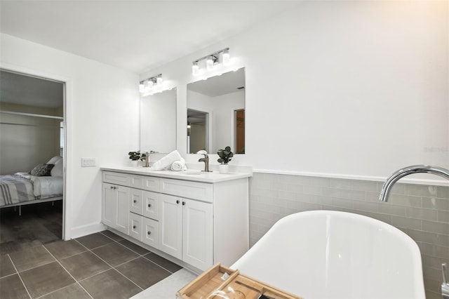 bathroom with tile patterned flooring, a washtub, tile walls, and vanity