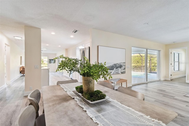 dining room with a textured ceiling, light hardwood / wood-style floors, and plenty of natural light