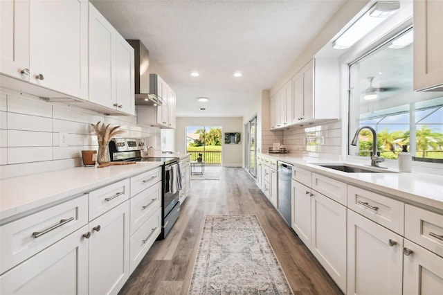 kitchen featuring white cabinetry, sink, wall chimney exhaust hood, dark hardwood / wood-style flooring, and appliances with stainless steel finishes