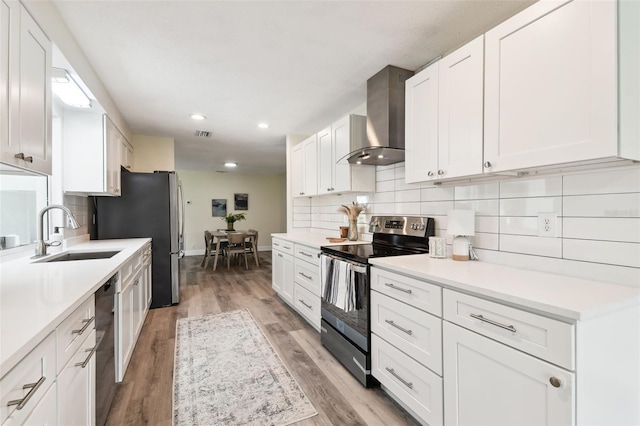 kitchen featuring white cabinets, stainless steel appliances, wall chimney exhaust hood, and sink