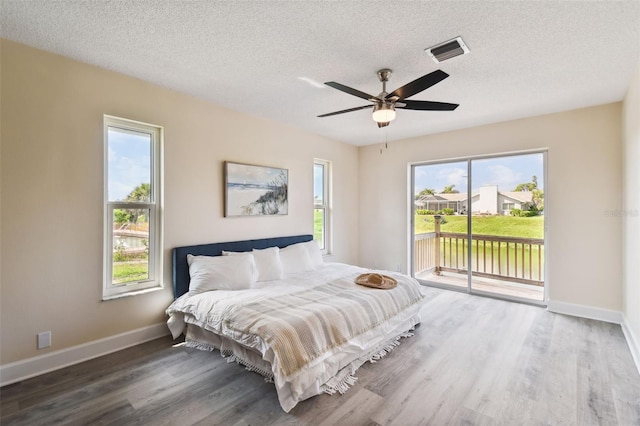 bedroom featuring access to outside, ceiling fan, wood-type flooring, and a textured ceiling