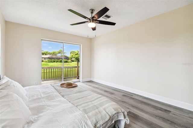 bedroom with hardwood / wood-style floors, ceiling fan, a textured ceiling, and access to outside