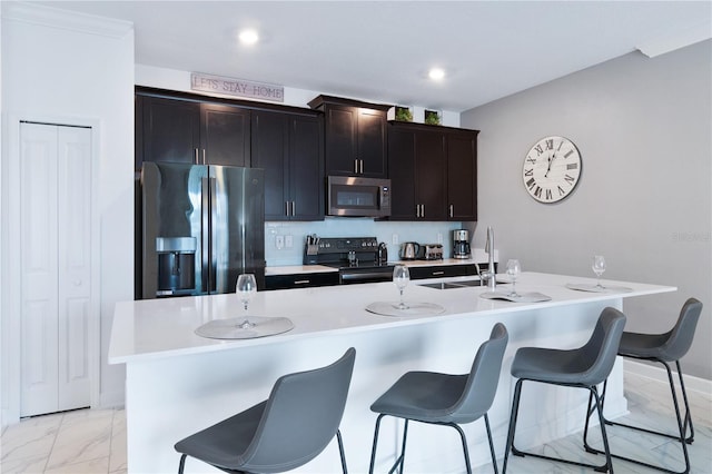 kitchen featuring a kitchen bar, a center island with sink, stainless steel appliances, and sink