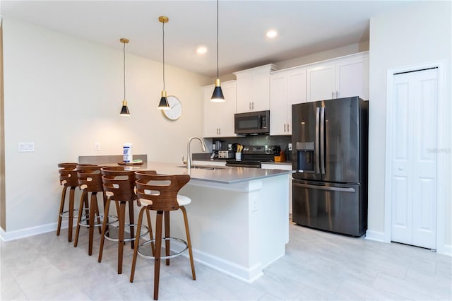 kitchen with white cabinetry, sink, hanging light fixtures, a kitchen breakfast bar, and appliances with stainless steel finishes