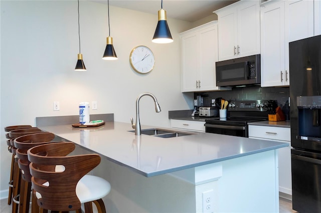 kitchen featuring black appliances, a kitchen breakfast bar, decorative backsplash, and sink