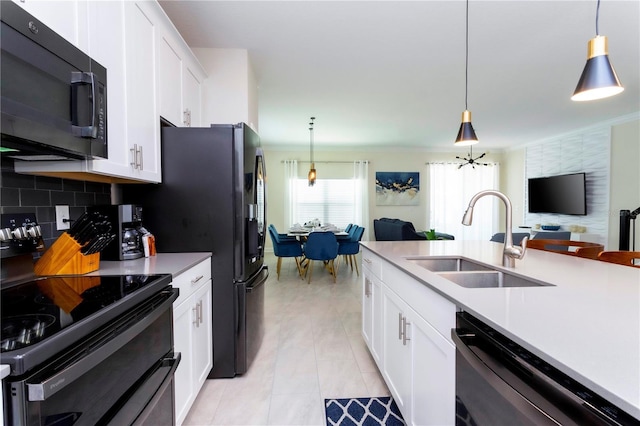 kitchen featuring pendant lighting, black appliances, white cabinets, crown molding, and sink