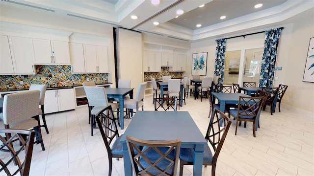 dining space featuring light tile patterned floors and a raised ceiling