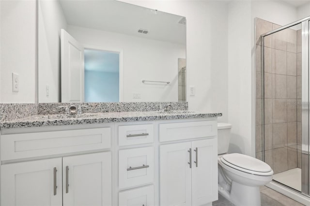 bathroom featuring tile patterned flooring, vanity, a shower with shower door, and toilet