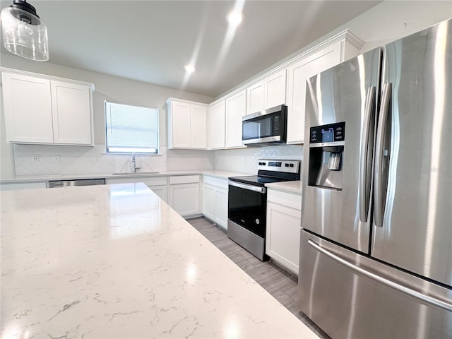 kitchen featuring white cabinetry, light stone countertops, sink, hanging light fixtures, and appliances with stainless steel finishes